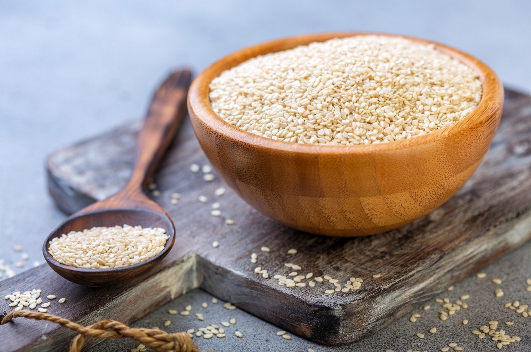 White sesame seeds in a wooden bowl and spoon.